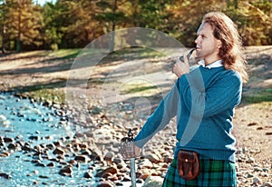 Handsome scottish man with sword and pipe