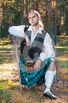 Handsome scottish man with sword and pipe