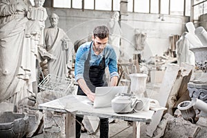 Sculptor working with laptop in the studio