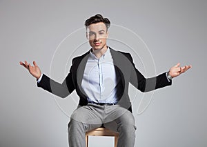 Handsome seated businessman making a welcoming hand gesture