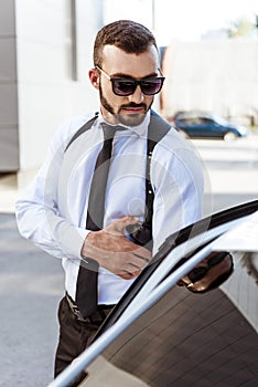 handsome security guard touching gun and opening