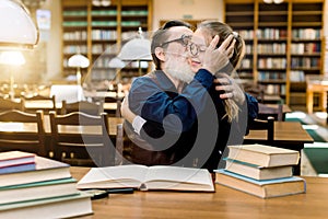 Handsome senior bearded man grandfather hugging and kissing his cute granddaughter, little girl in eyeglasses, sitting