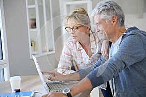 Handsome senior couple at home using laptop