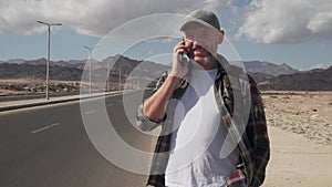 Handsome senior male talking by smatrphone standing on a road in desert