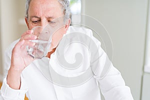 Handsome senior man drinking a fresh glass of water at home