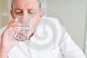 Handsome senior man drinking a fresh glass of water at home