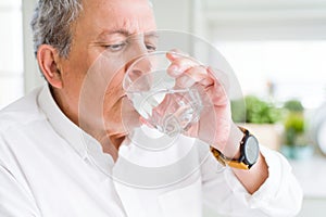 Handsome senior man drinking a fresh glass of water at home