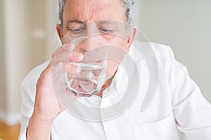 Handsome senior man drinking a fresh glass of water at home