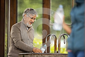 Handsome senior man drinking mineral water in a spa/health resort