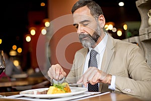 Handsome senior man eating lunch in restaurant