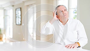 Handsome senior man at home confuse and wonder about question
