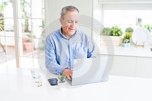 Handsome senior man using laptop and smiling