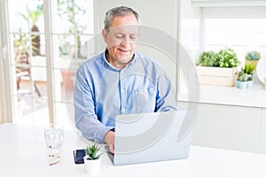 Handsome senior man using laptop and smiling
