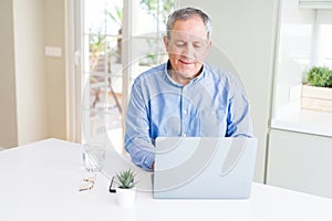 Handsome senior man using laptop and smiling