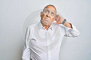 Handsome senior man wearing casual white shirt confuse and wondering about question