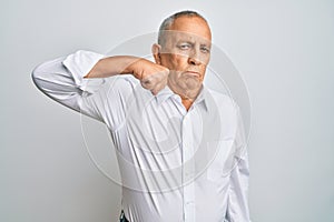 Handsome senior man wearing casual white shirt strong person showing arm muscle, confident and proud of power