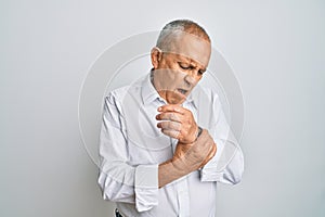Handsome senior man wearing casual white shirt suffering pain on hands and fingers, arthritis inflammation