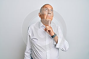 Handsome senior man wearing casual white shirt thinking concentrated about doubt with finger on chin and looking up wondering