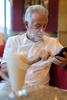 Handsome senior tourist man relaxing inside the coffee shop