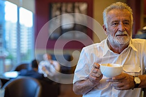 Handsome senior tourist man relaxing inside the coffee shop