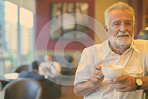 Handsome senior tourist man relaxing inside the coffee shop