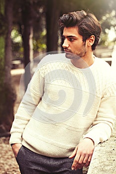 Handsome serene and pensive young man model in a trees park