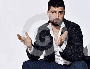 Handsome serious brunette brutal businessman in stylish official suit and shirt sitting and gesticulating during communication photo