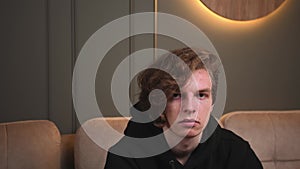 Handsome serious caucasian man looking at camera, sitting on couch at home.