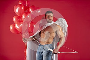 Handsome sexy angels. Valentines day. Muscular guy posing as angel. Cupid in love holding colorful balloons and bow and