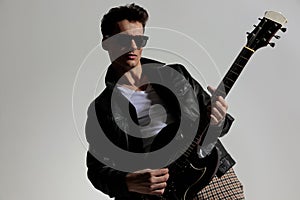 handsome sexy man with glasses playing guitar and being cool