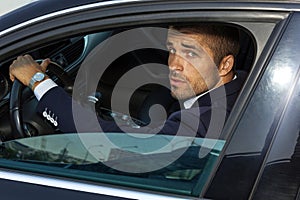 A handsome sexy man in a suit driving a car. Portrait