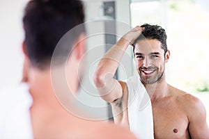 Handsome shirtless man looking in the mirror