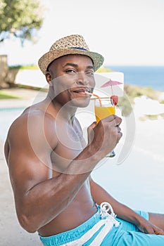 Handsome shirtless man relaxing with cocktail poolside
