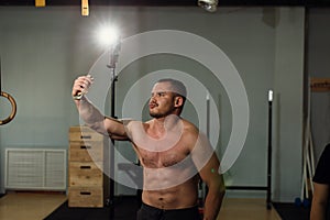 Handsome shirtless muscular bodybuilder man taking selfie with cell phone
