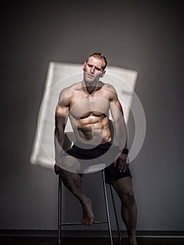 Handsome shirtless muscular man posing in gym