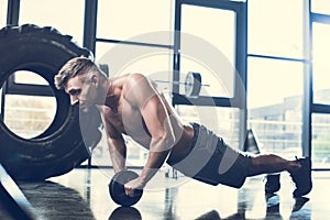 handsome shirtless sportsman exercising with abs roller photo