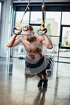 handsome shirtless sportsman exercising with resistance bands photo