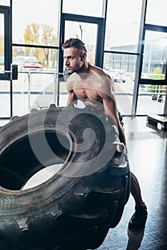 handsome shirtless sweaty sportsman lifting tire photo