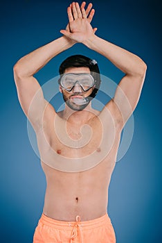 handsome shirtless young man in shorts and diving mask raising hands and looking at camera