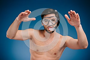 handsome shirtless young man in snorkel and diving mask swimming and looking at camera
