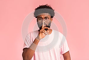 Handsome silent black man with glasses making hush gesture
