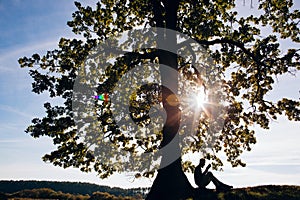 Handsome silhouette Young bearded student man hipster reading book in park on a summers sunny day. Relax concept