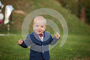 Handsome smile portrait baby. 1 year old cute boy on the grass. Birthday anniversary.