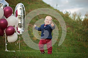 Handsome smile portrait baby. 1 year old cute boy on the grass. Birthday anniversary.