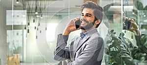 Handsome smiling business man talking on mobile phone in office