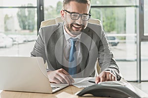 handsome smiling businessman using speakerphone