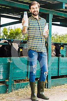 handsome smiling farmer holding bottles of cow milk