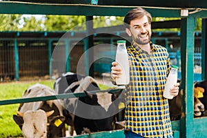 handsome smiling farmer showing cow milk