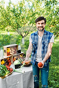 handsome smiling farmer showing ripe ecological vegetables