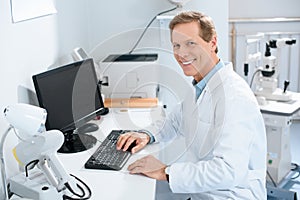 handsome smiling male ophthalmologist working with computer